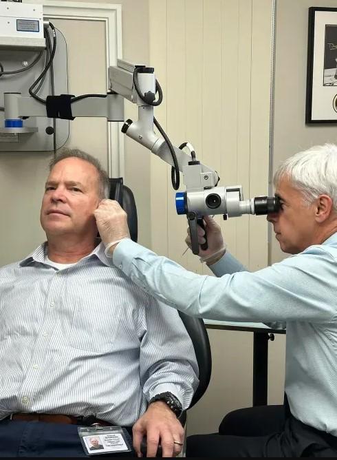 Dr. John Martinetti, Au.D examining patient's ear