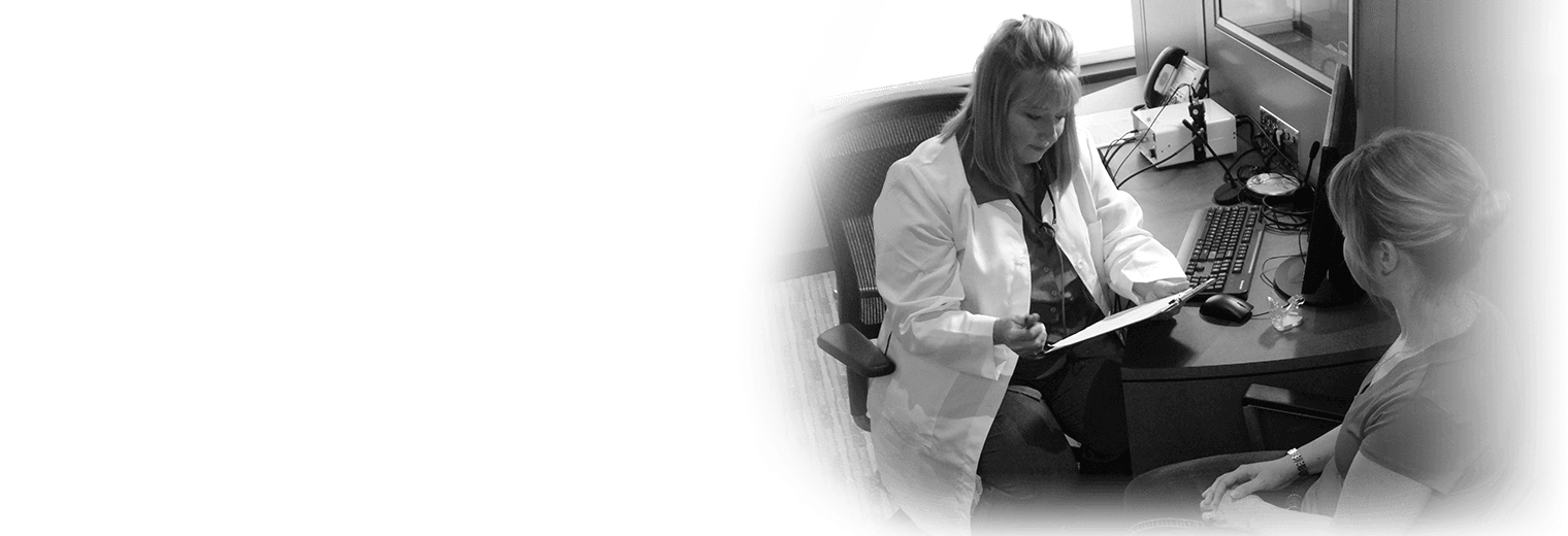 A woman sets at a desk with an audiologist.