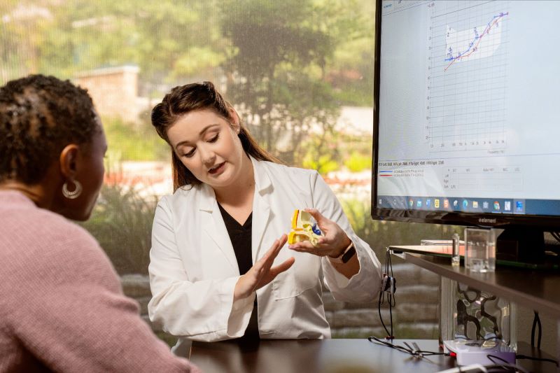 A woman talks to her audiologist at a hearing care appointment. 