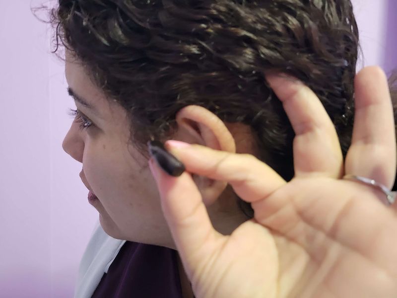 Carmen Cusido displays her hearing aid for mid-range hearing loss. 