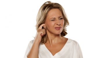 A woman scratches her ear. 