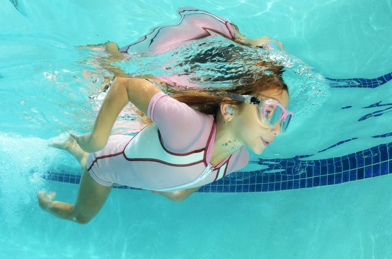 A girl swims with ear plugs in her ears.