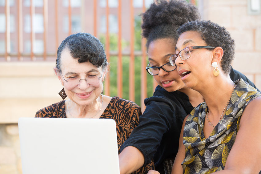 A family gathers around a laptop.