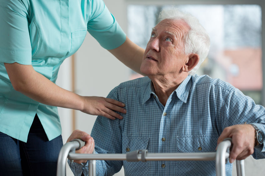 An older man looks up at a caregiver.