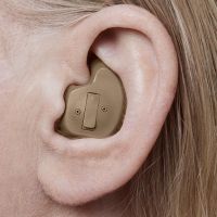 A picture or image of a full-shell low-profile hearing aid worn by a woman. 