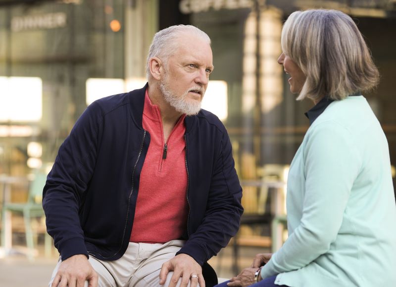 A man struggles to hear a woman talking. 