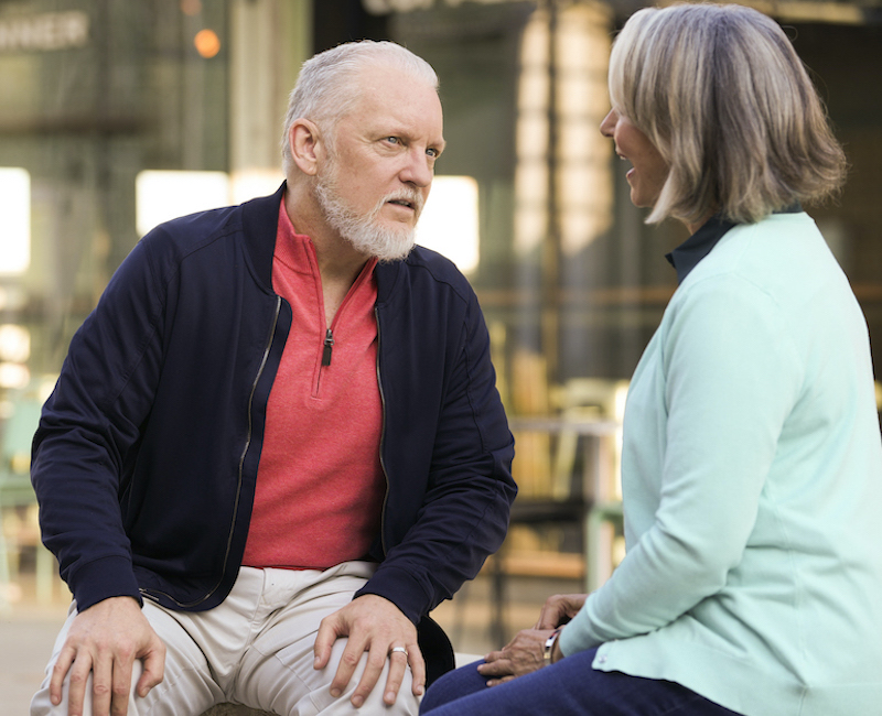 A man strains to hear a person talking to him. 