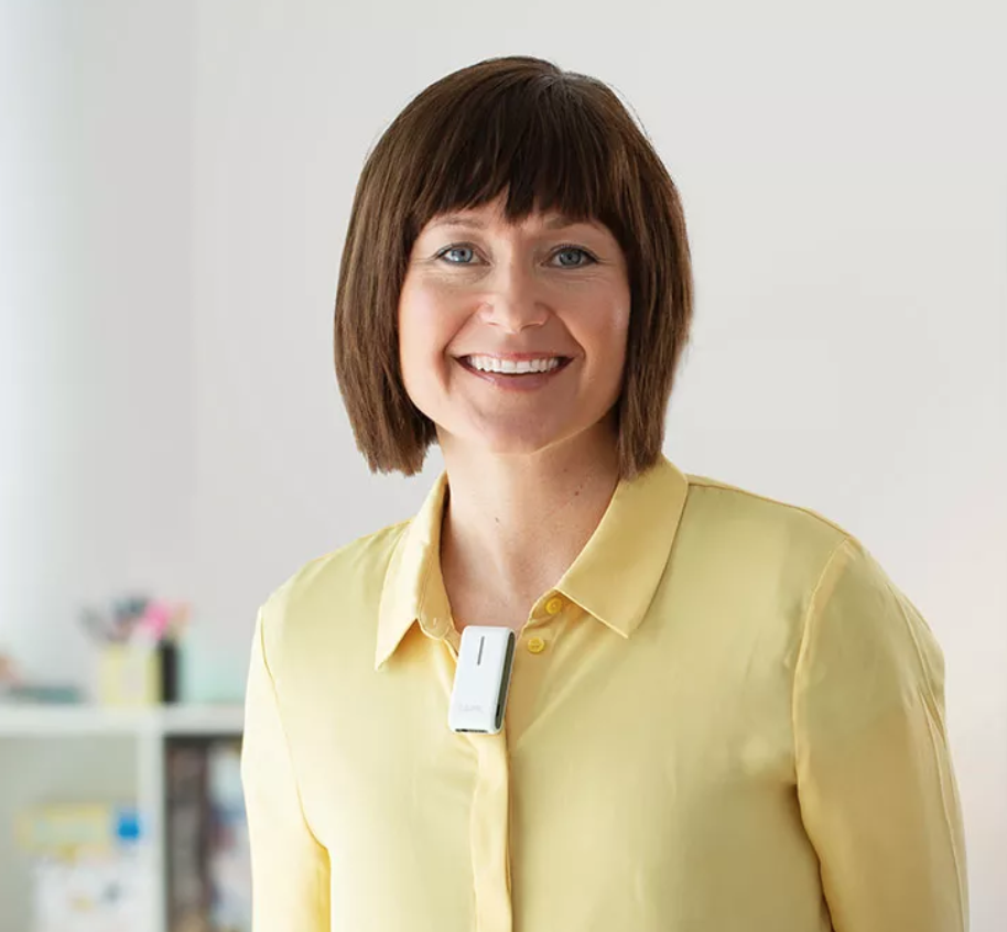 A woman in a yellow shirt wearing a remote microphone.