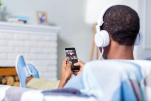 A man with headphones on looks at his phone.