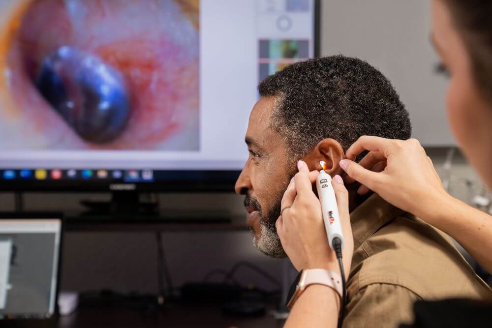 A hearing care provider peers into a patient's ear canal.