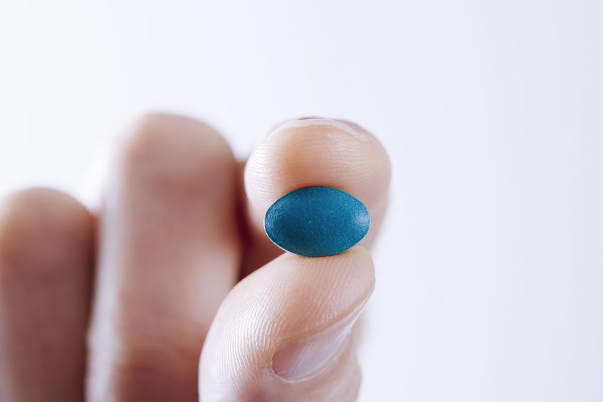 A man holds a Viagra tablet.