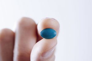 A man holds a Viagra tablet.