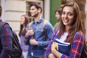 young woman holding textbooks on campus