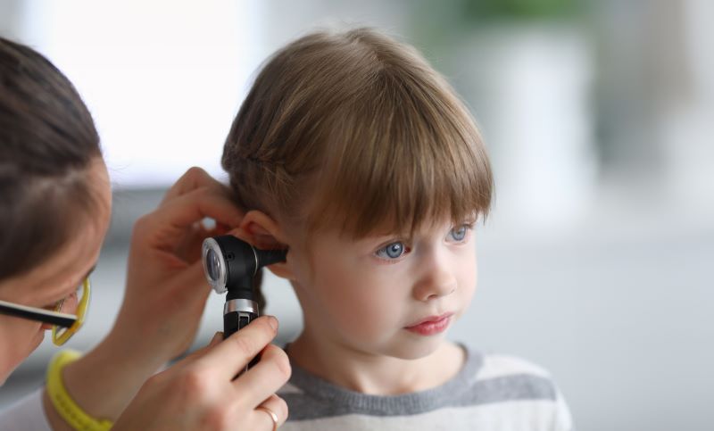 A young girl receives an ear exam to check for an infection. 