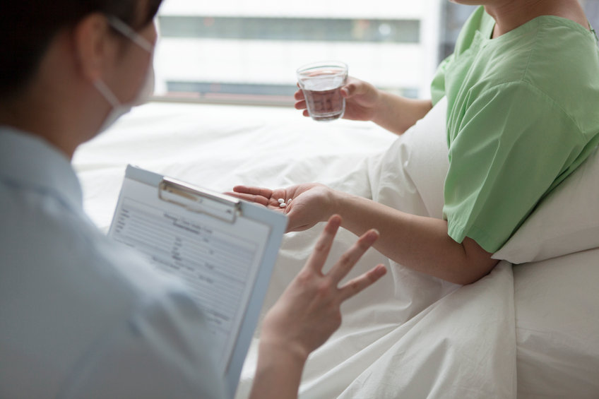 A hospital worker talks to a patient in a hospital bed. 