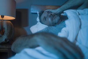 A man is awake at night with tinnitus.