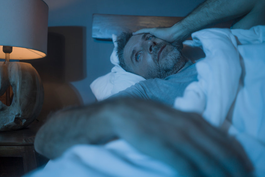 A man is awake at night, in bed. 
