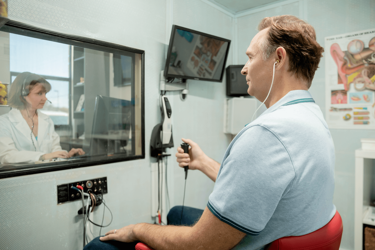 Man getting a comprehensive hearing test in a booth
