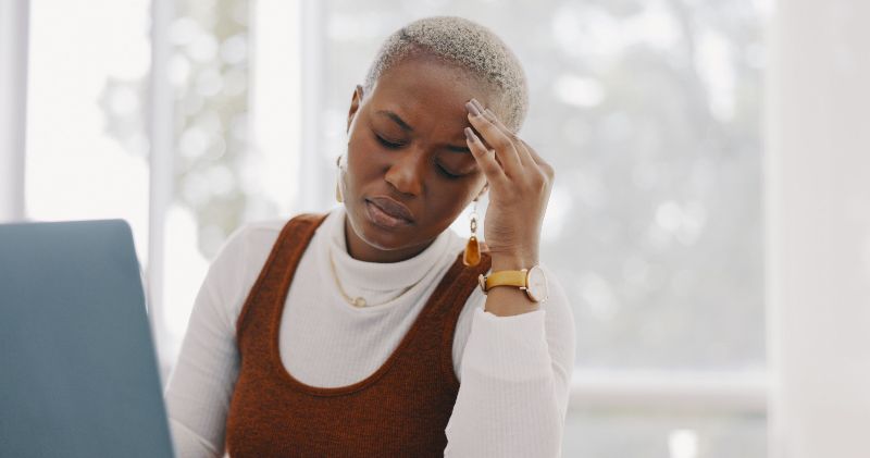 A woman grips her forehead.