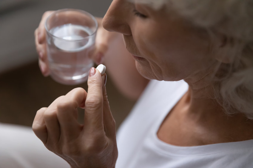 A woman takes a white capsule.